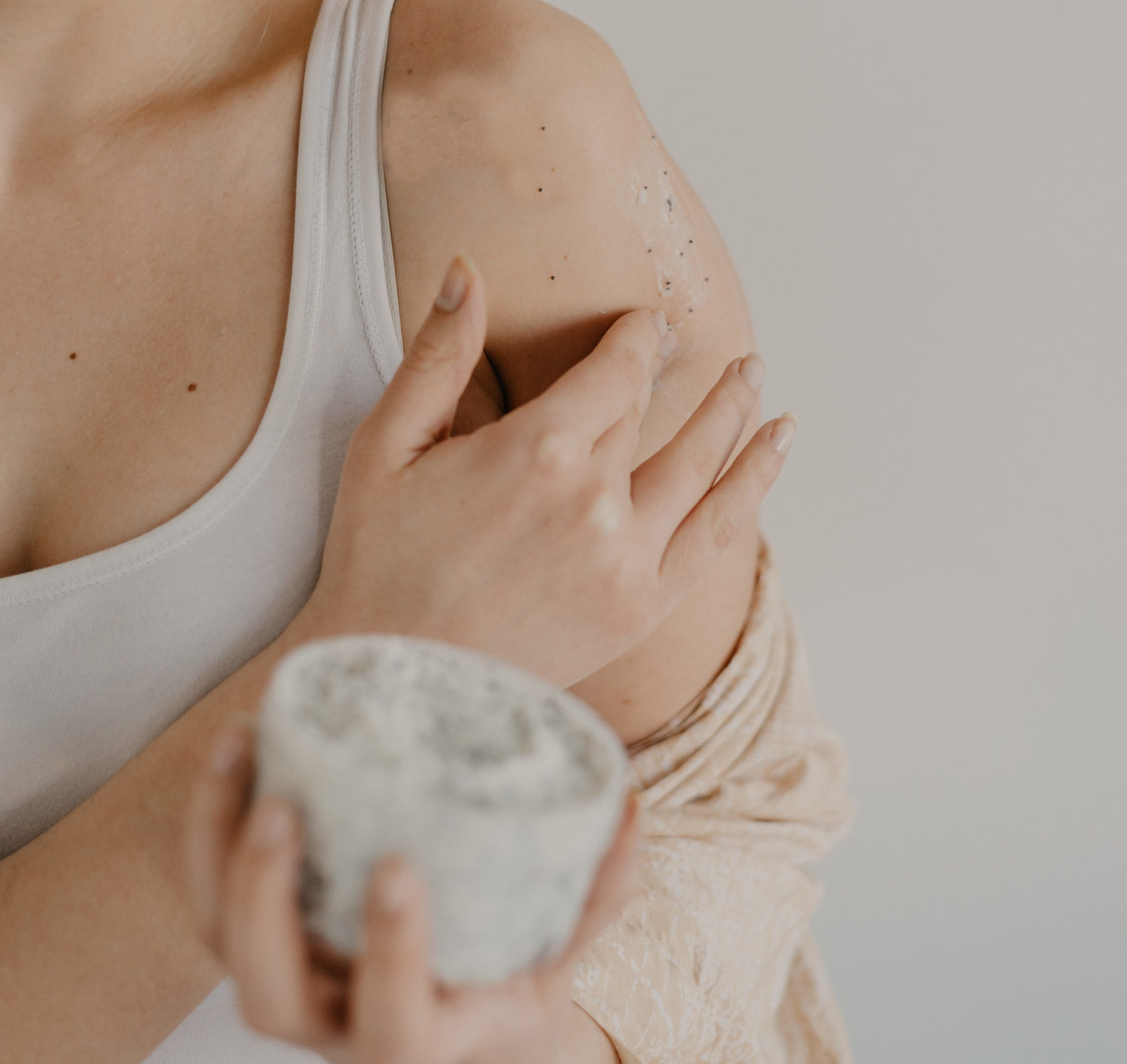 Woman applying skin exfoliant treatment on skin, part of detoxifying therapies.