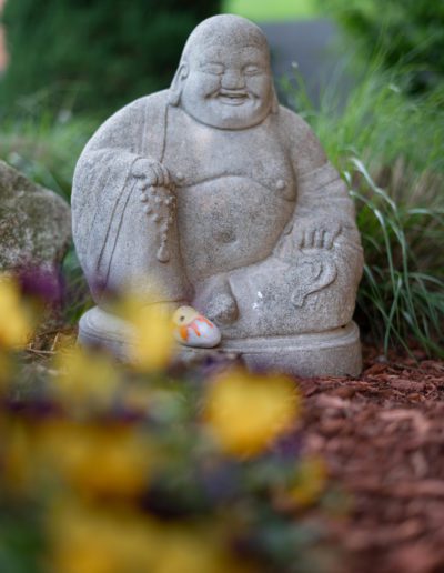 Stone Buddha statue in Raffa's outdoor garden setting.
