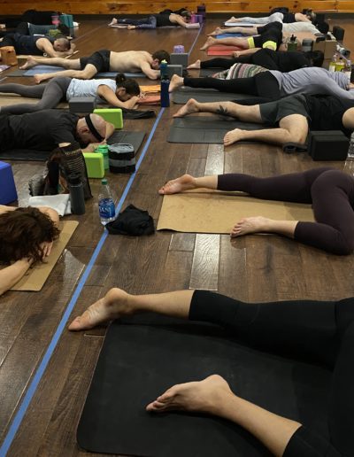 Yoga participants in a relaxation pose on mats.