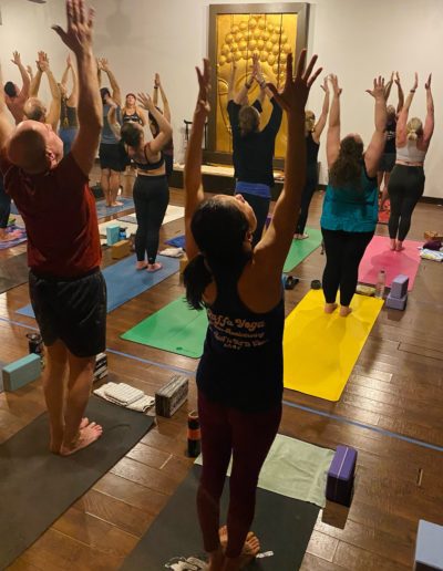 Yoga class reaching upward in a studio.